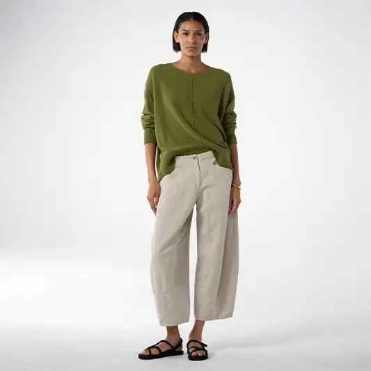 Woman wearing green sweater and light pants.