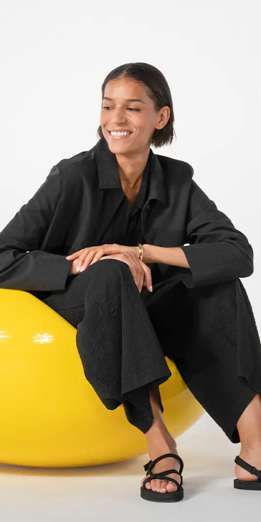Femme souriant assise sur un ballon jaune.