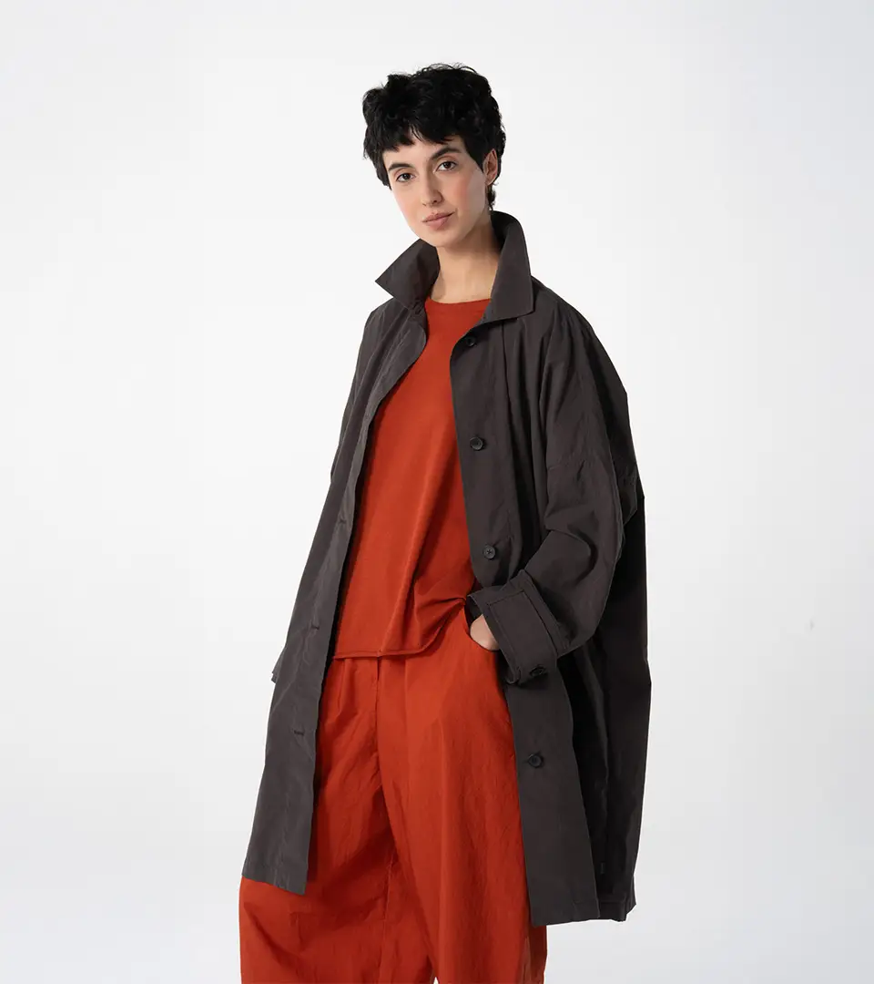 Woman in stylish outfit, dark coat and orange top.