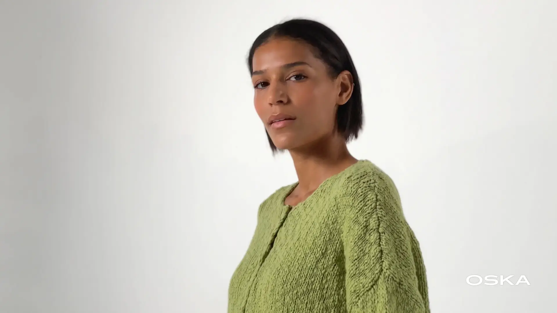 Model wearing a green sweater on white background.