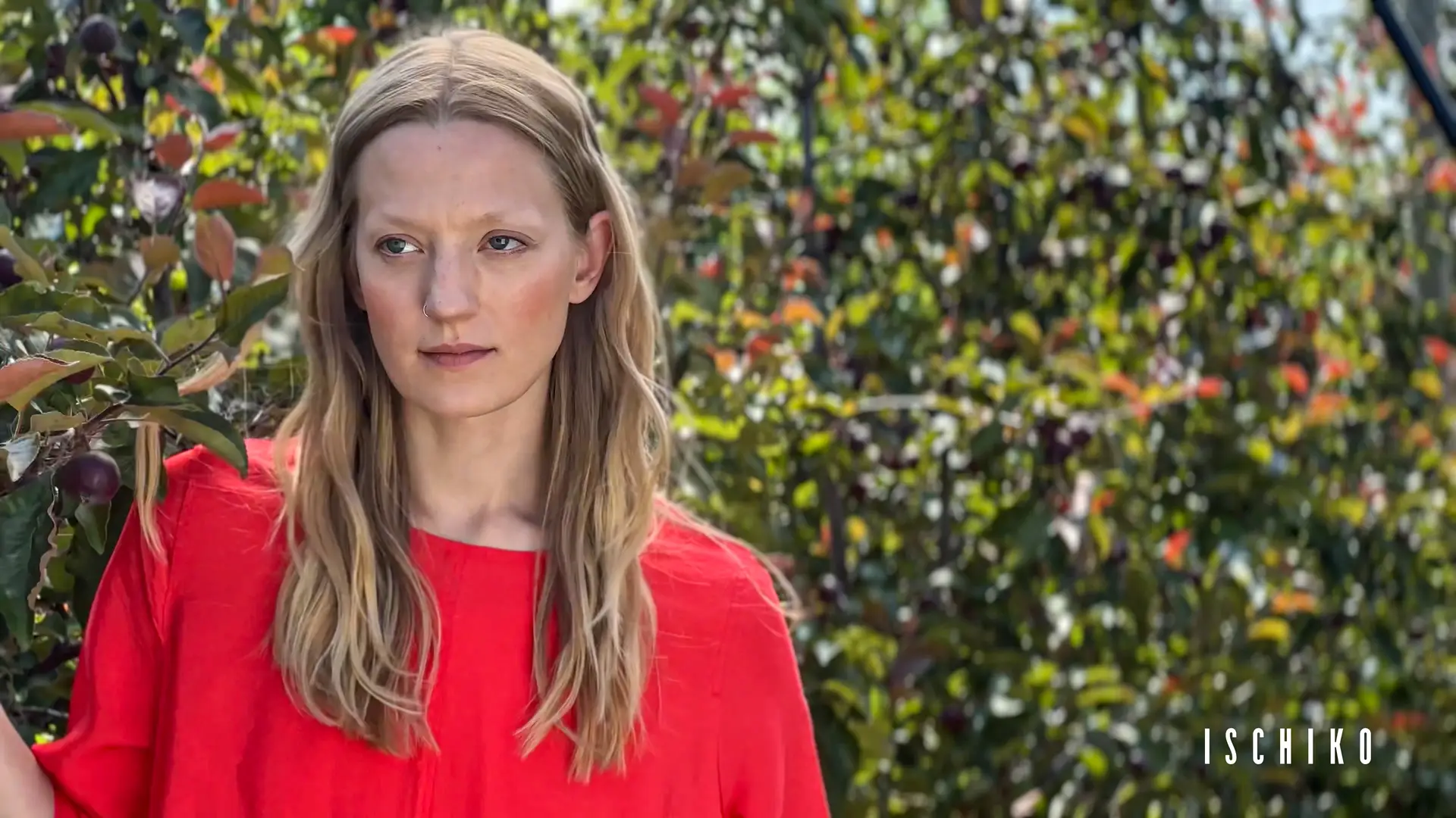 Woman in red shirt among greenery.