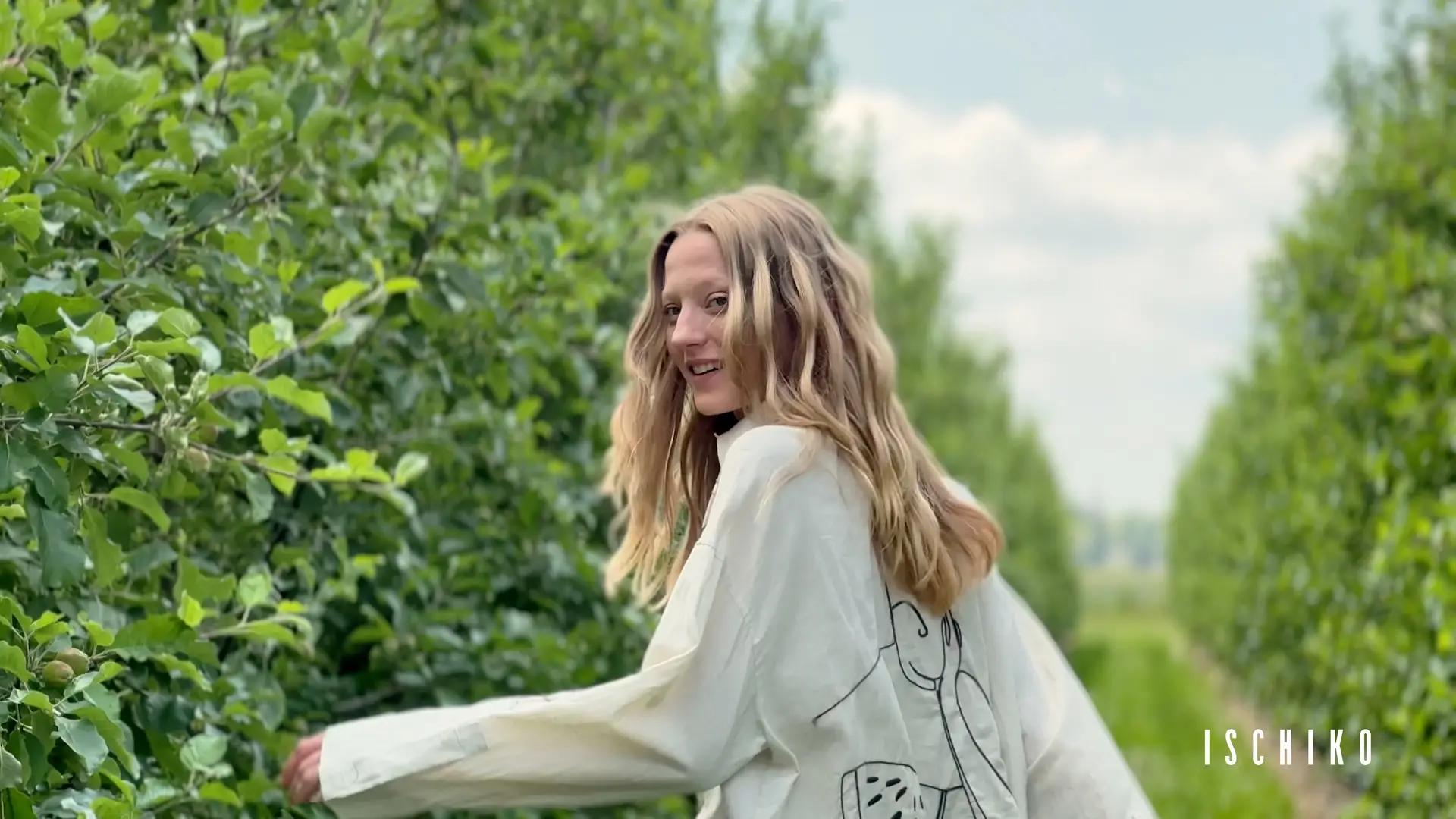 Woman smiling in an apple orchard.