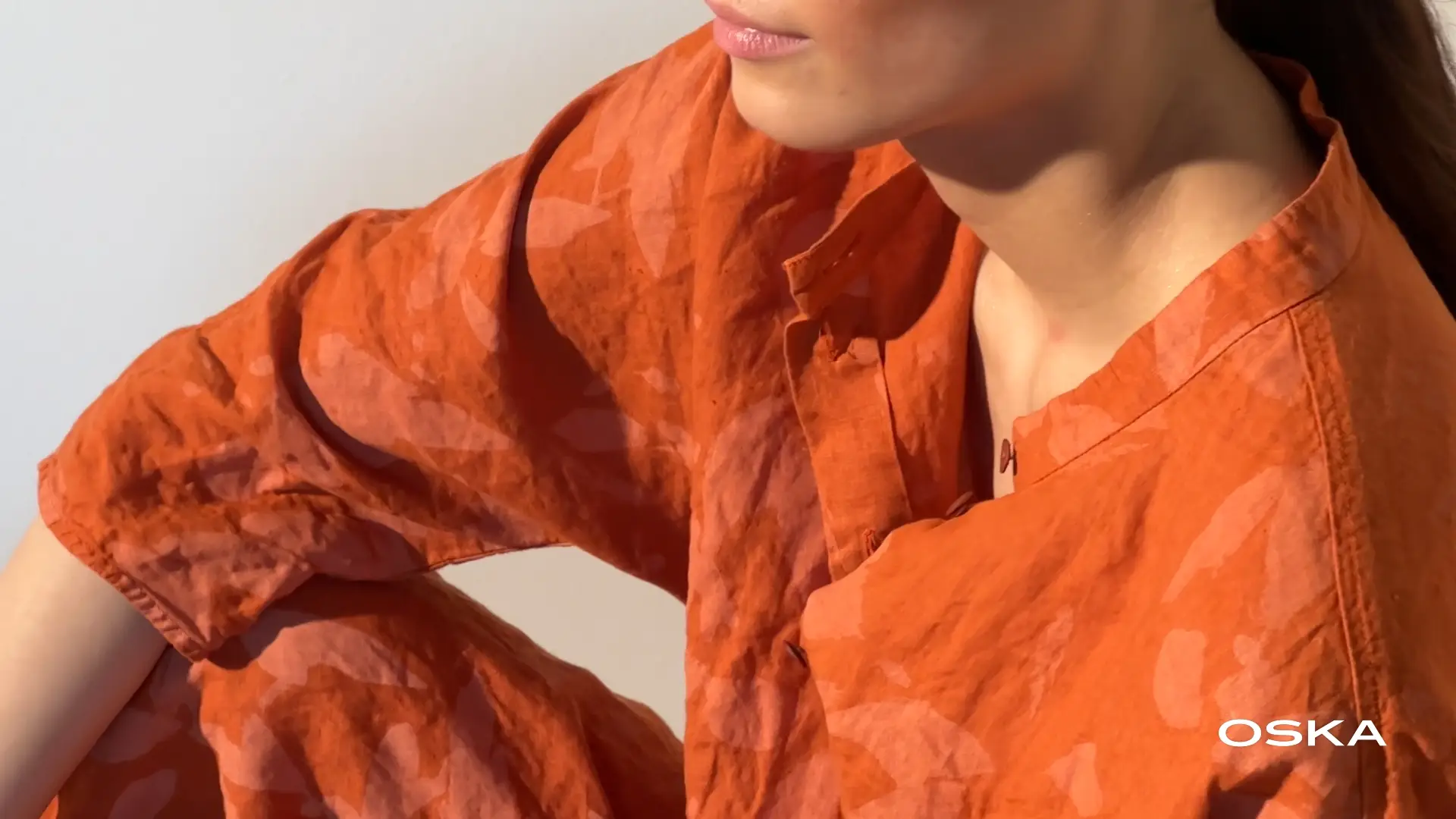 Close-up of a model wearing an orange outfit.