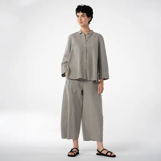 Person in gray outfit standing confidently