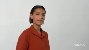 Woman in rust blouse against plain background