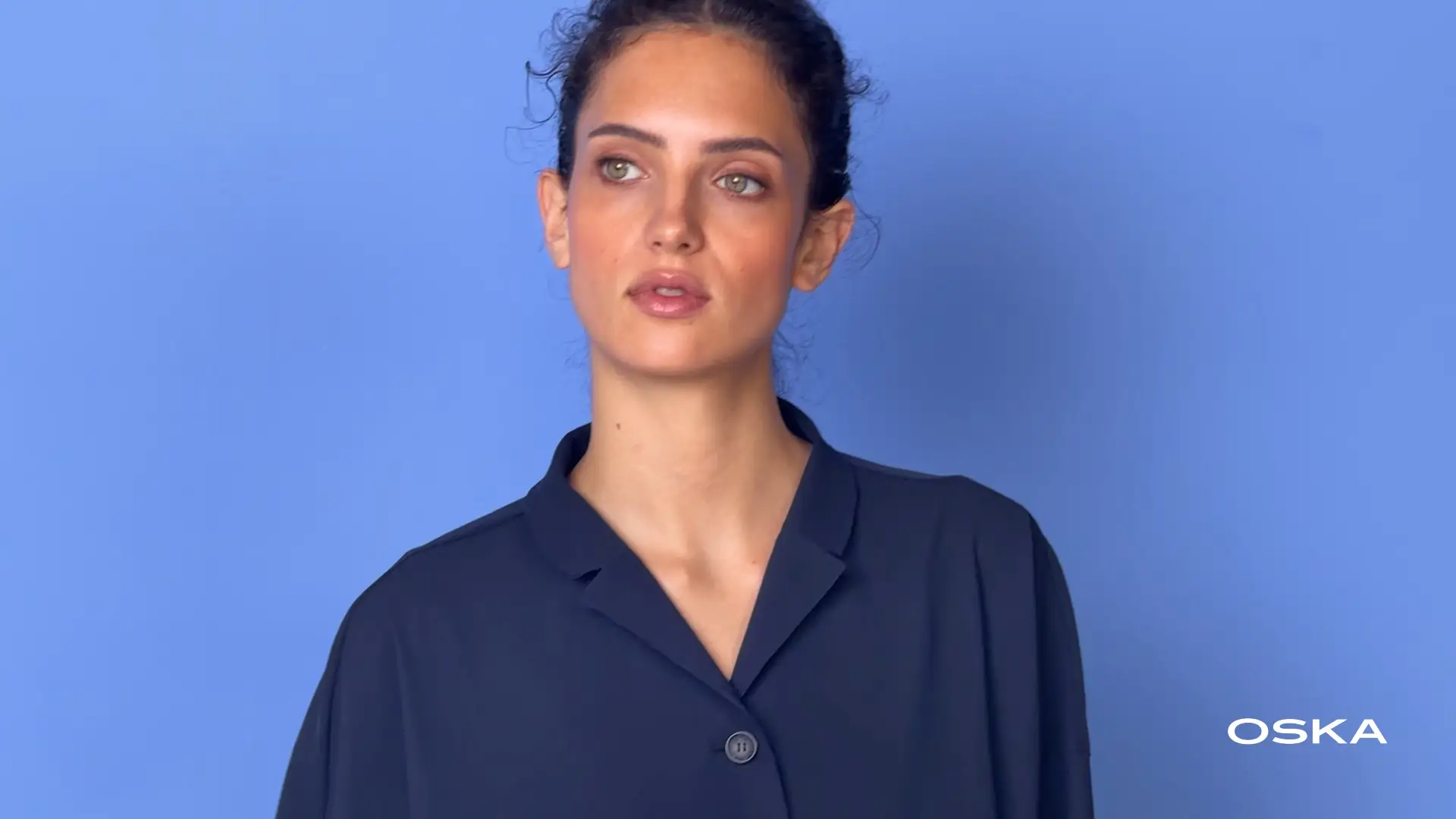 Woman in navy blouse against blue background