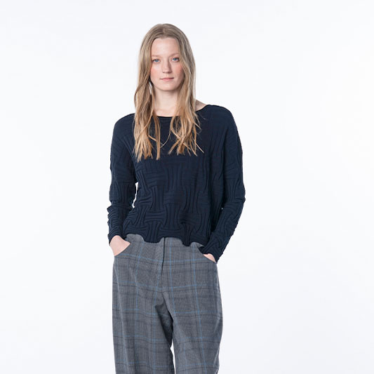 Woman wearing a navy textured sweater and grey plaid trousers