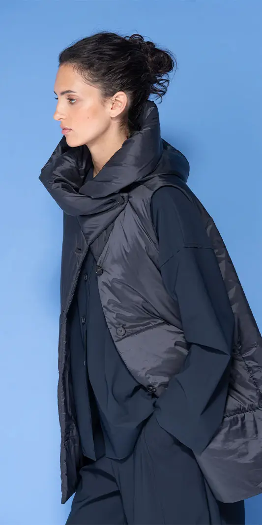 Žena v tmavomodré prošívané oversized vestě.
