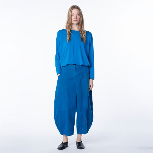 Woman in a bright blue top and wide-leg trousers.