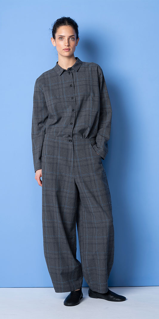 Woman wearing a gray plaid matching set against blue background.