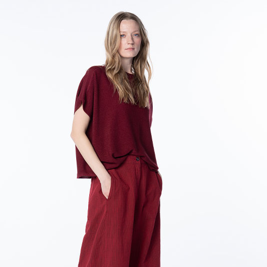 Woman wearing burgundy knit top and red wide-leg pants.