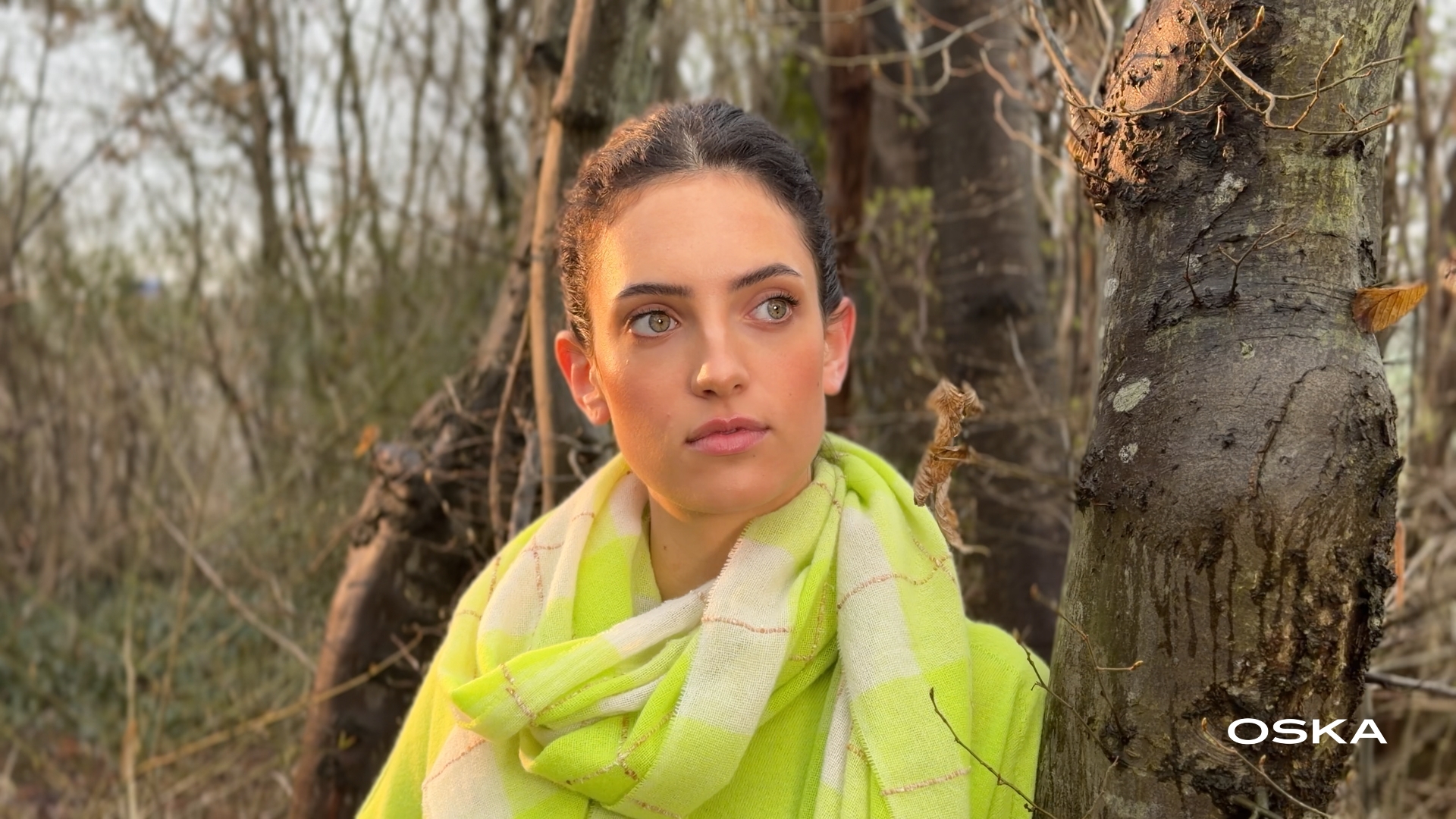 Woman with green eyes wearing a lime green scarf outdoors.