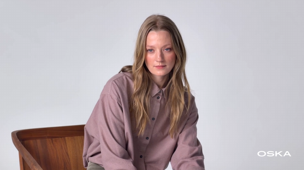 Woman with long blonde hair wearing a mauve shirt.